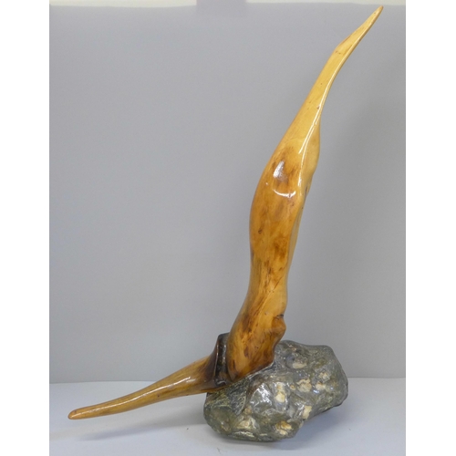 616 - A lacquered driftwood sculpture on a stone base