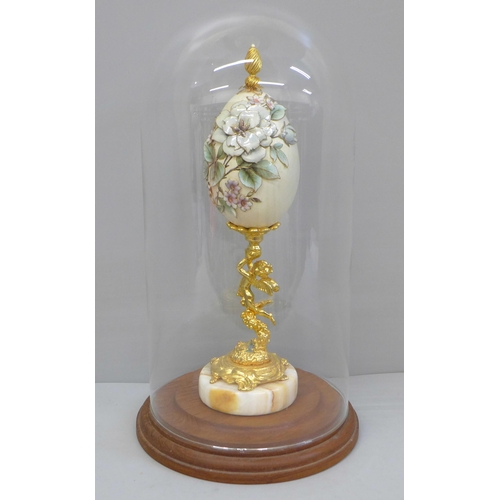 673 - A hand decorated egg on stand, with glass dome