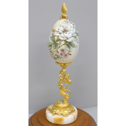 673 - A hand decorated egg on stand, with glass dome