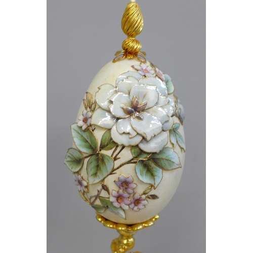 673 - A hand decorated egg on stand, with glass dome