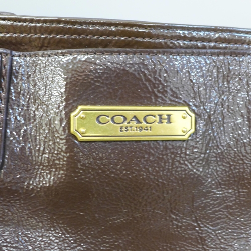 722 - A Coach patent handbag in brown, with pink satin lining, top zip fastening and a variety of pockets ... 