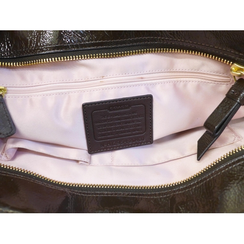 722 - A Coach patent handbag in brown, with pink satin lining, top zip fastening and a variety of pockets ... 