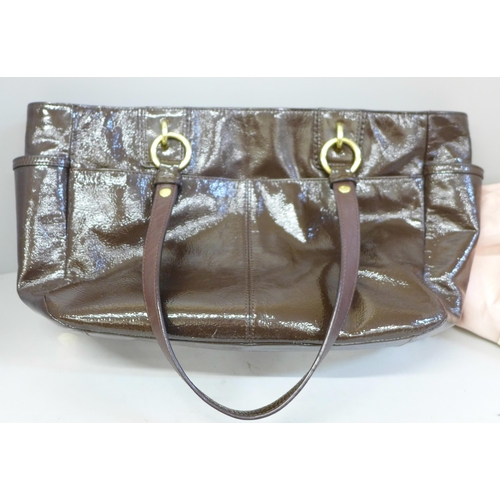 722 - A Coach patent handbag in brown, with pink satin lining, top zip fastening and a variety of pockets ... 