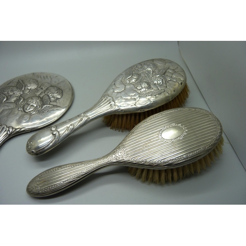 938 - Silver backed brushes and mirrors including two embossed with Reynolds Angels, one brush silver plat... 