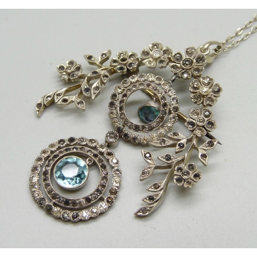 1030 - A silver pendant/brooch set with paste stones on a silver chain, marked 925, 43mm wide