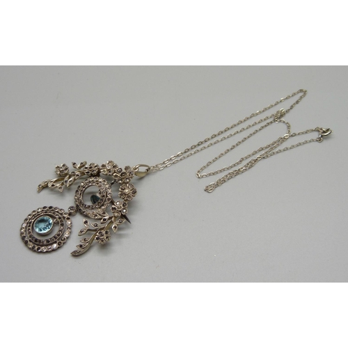 1030 - A silver pendant/brooch set with paste stones on a silver chain, marked 925, 43mm wide