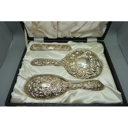 885 - A cased three piece silver hand mirror and brush set, Birmingham 1982