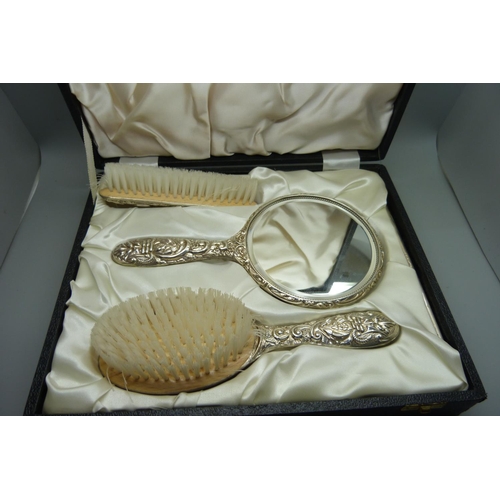 885 - A cased three piece silver hand mirror and brush set, Birmingham 1982