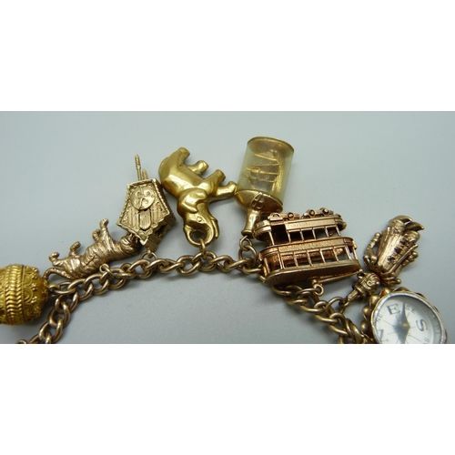 964 - A 9ct gold charm bracelet, with twelve hallmarked 9ct gold charms and a yellow metal charm, 73.3g