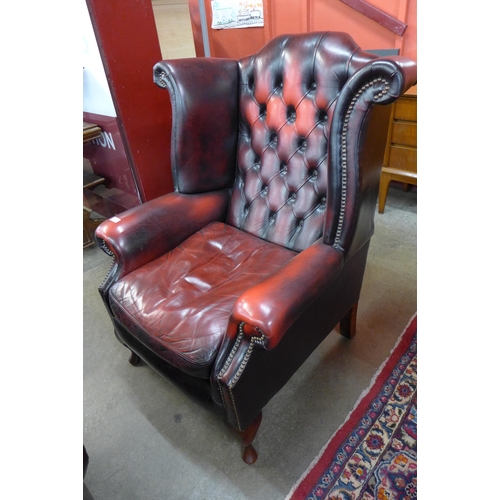 112 - An oxblood red leather Chesterfield wingback armchair