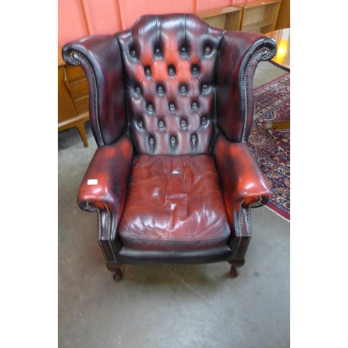 112 - An oxblood red leather Chesterfield wingback armchair