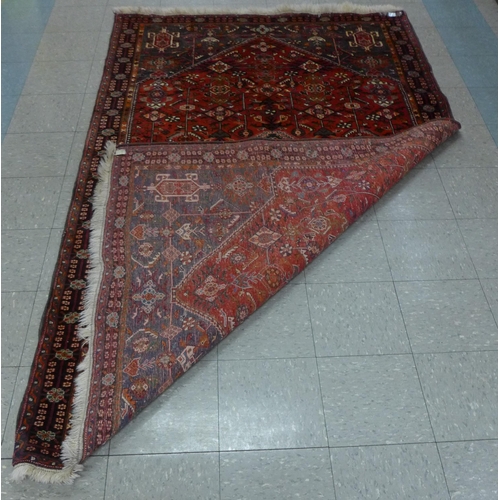 138 - An Iranian Qashqai woollen pile, wool foundation red ground rug, 162 x 260cms