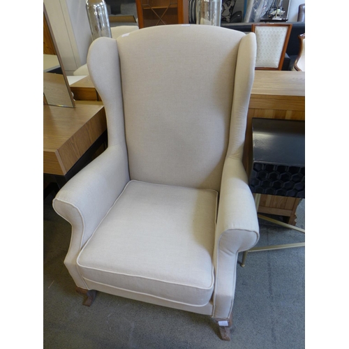 1582 - An oatmeal upholstered wingback chair with patterned scatter cushion