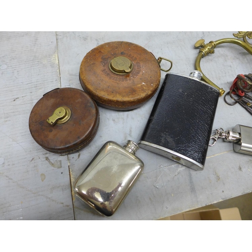 Assorted items; hip flasks, keys, tape measures, a wall light fitting