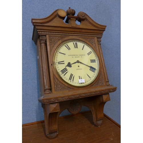 84 - A Victorian carved oak wall clock, the painted circular dial signed Goldsmiths Company, 112 Regent S... 