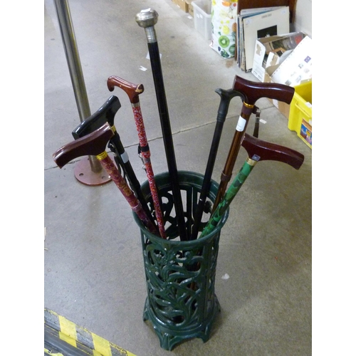 723 - Seven walking canes in cast iron stick stand