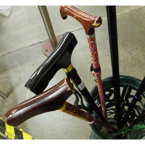 723 - Seven walking canes in cast iron stick stand