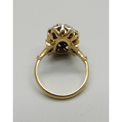 983 - A yellow and white metal ring set with a red stone, marked 750, 5.1g, L