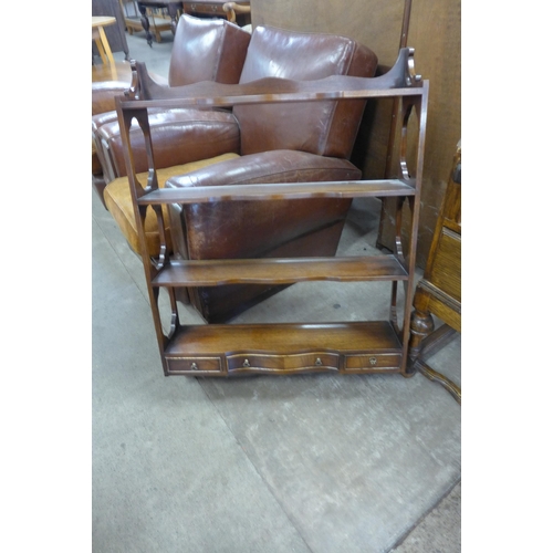 144 - An oak bureau, a mahogany coffee table and mahogany wall hanging shelves