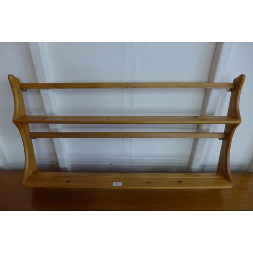 37 - An Ercol pine wall hanging plate rack