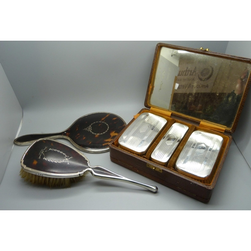 874 - A silver brush set, a silver and tortoiseshell hand mirror and a similar brush