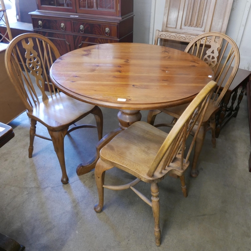 232 - A circular pine kitchen table and three beech Windsor style wheelback chairs