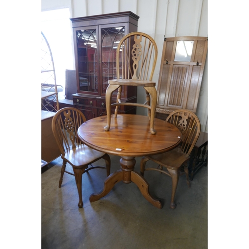 232 - A circular pine kitchen table and three beech Windsor style wheelback chairs