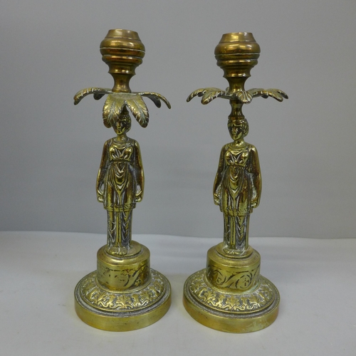 671 - A pair of brass figural candlesticks modelled as a woman taking shade under a palm tree