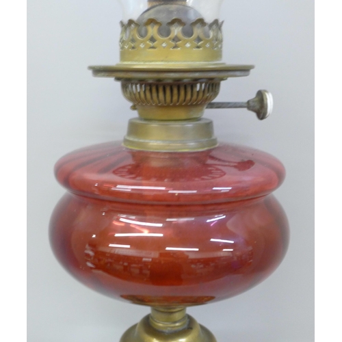 780 - A Victorian or Edwardian Hinks oil lamp with cranberry glass reservoir, on a brass Art Nouveau base