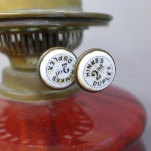 780 - A Victorian or Edwardian Hinks oil lamp with cranberry glass reservoir, on a brass Art Nouveau base