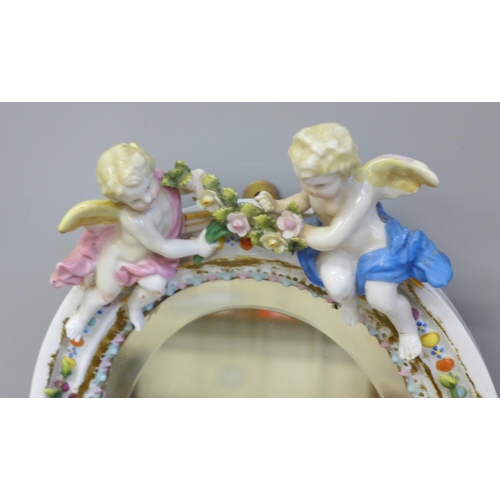 805 - A flower encrusted porcelain mirror decorated with cherubs