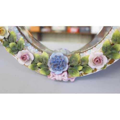 805 - A flower encrusted porcelain mirror decorated with cherubs