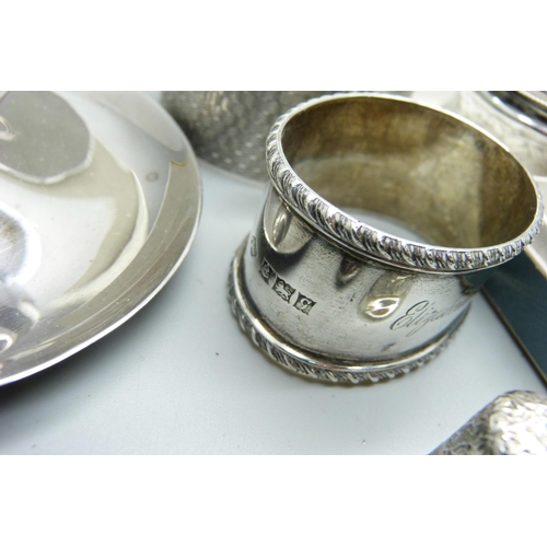 935 - Three silver napkin rings, 62g, a pair of silver salt spoons, a silver thimble, three glass salts an... 