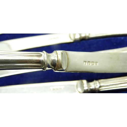 957 - A cased set of six butter knives, silver covered handles