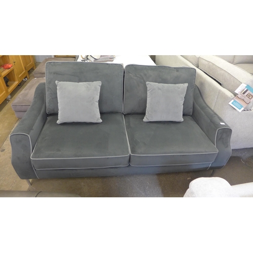 1514 - A mid grey velvet upholstered small three seater sofa with light grey piping and scatter cushions on... 