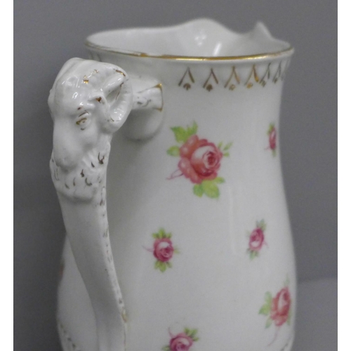 603 - A jug decorated with hand painted roses and a ram's head handle, with raised 'Adam' mark to base, 21... 