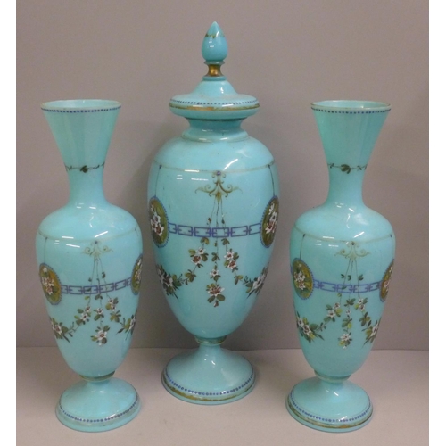 794 - A pair of blue opaline glass vases and one taller lidded vase, enamel painted of swags of flowers an... 