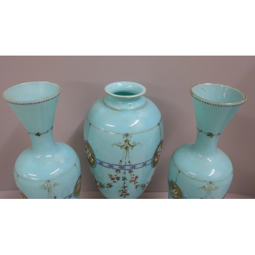 794 - A pair of blue opaline glass vases and one taller lidded vase, enamel painted of swags of flowers an... 