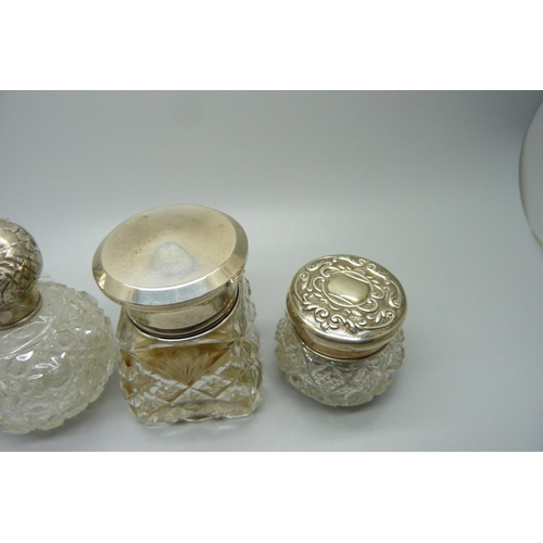 849 - Four silver topped glass scent bottles/dressing table pots, including a scent bottle in the shape of... 