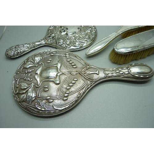 893 - A silver backed Art Nouveau hand mirror, Birmingham 1906, one other mirror, a/f, and two silver back... 