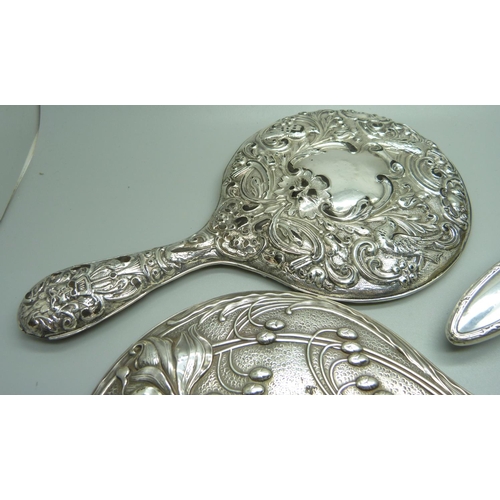 893 - A silver backed Art Nouveau hand mirror, Birmingham 1906, one other mirror, a/f, and two silver back... 