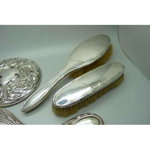 893 - A silver backed Art Nouveau hand mirror, Birmingham 1906, one other mirror, a/f, and two silver back... 