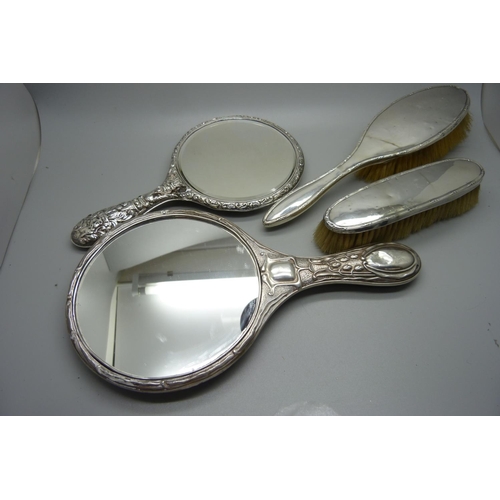 893 - A silver backed Art Nouveau hand mirror, Birmingham 1906, one other mirror, a/f, and two silver back... 