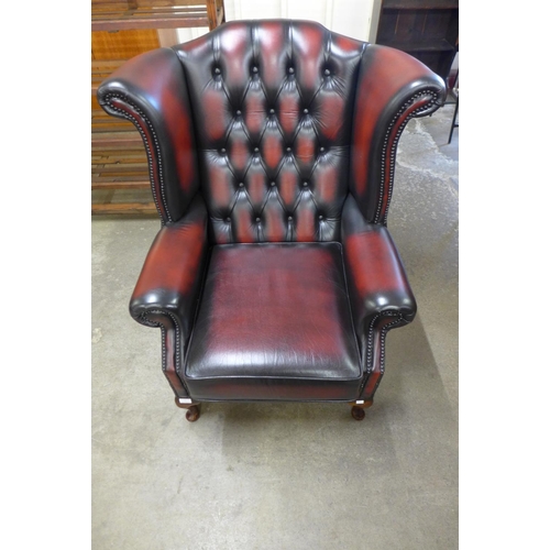 2 - An oxblood red leather Chesterfield wingback armchair