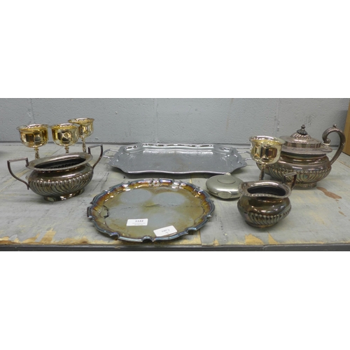 1122 - A collection of plated ware including trays, goblets, a three piece tea service and a pewter hip fla... 