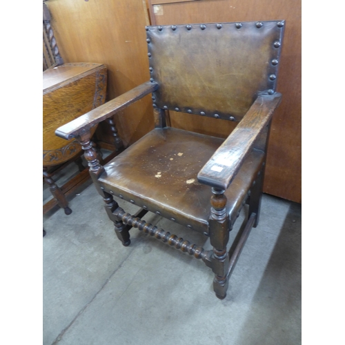 142 - An oak and brown leather upholstered armchair