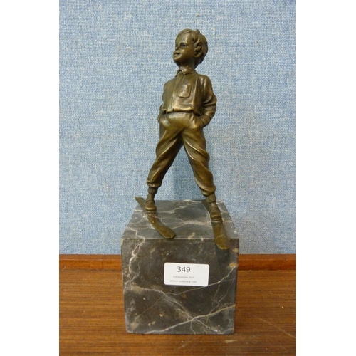 349 - A bronze figure of a young boy on skis, on grey marble socle