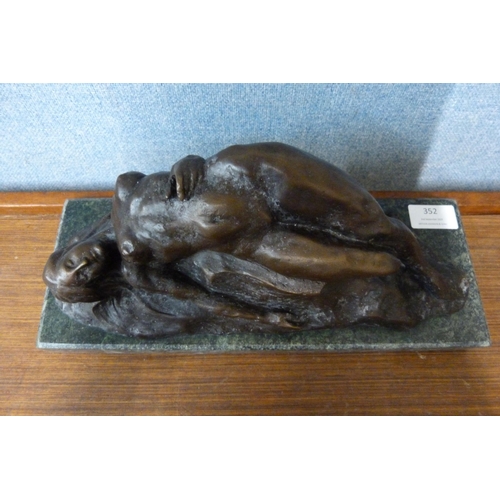 352 - An Art Deco style bronze figure of a reclining female nude on a rock, on black marble socle