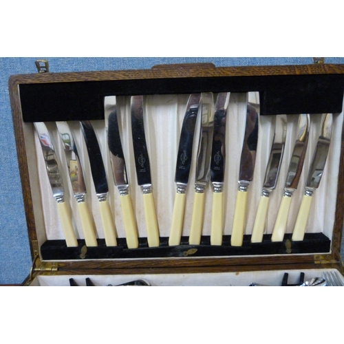 353 - An oak cased canteen of stainless steel and faux ivory cutlery