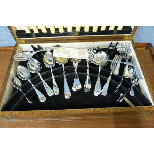 353 - An oak cased canteen of stainless steel and faux ivory cutlery